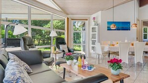 Un salon moderne comprenant un canapé, des fauteuils, une table à manger et un téléviseur.