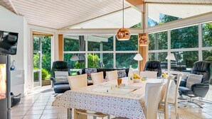 Un vaste espace dédié à la salle à manger, avec une grande table, des chaises et une vue sur l’extérieur grâce à de grandes fenêtres.