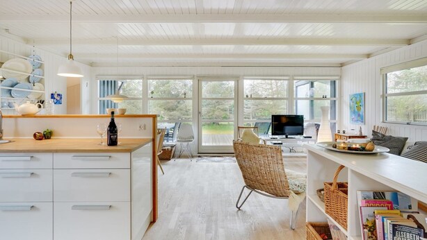 A spacious kitchen with white cabinetry, a wooden countertop, and a dining area with wicker chairs. - "Bernadeta" - 1.2km from the sea by Interhome (Blokhus)