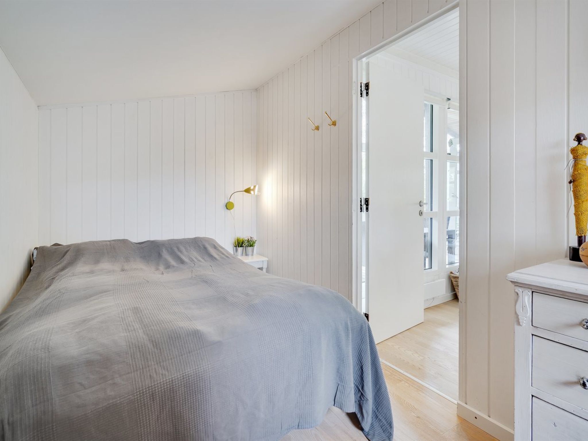 Een slaapkamer met een bed, nachtkastje, lamp en een garderobe.