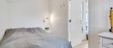 Een slaapkamer met een bed, nachtkastje, lamp en een garderobe.