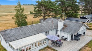 Een wit gebouw met een overdekte patio, een barbecue en een terras.