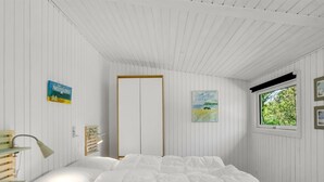 Un dormitorio con cama, mesita de noche, lámpara y ventana con vista a árboles.
