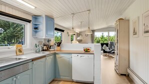 Una cocina moderna con armarios azul claro, un lavavajillas y una ventana con vistas a zonas verdes.
