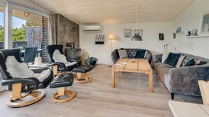 Una sala de estar moderna con chimenea de piedra, sillones de cuero, una mesa de centro de madera y un sofá gris.