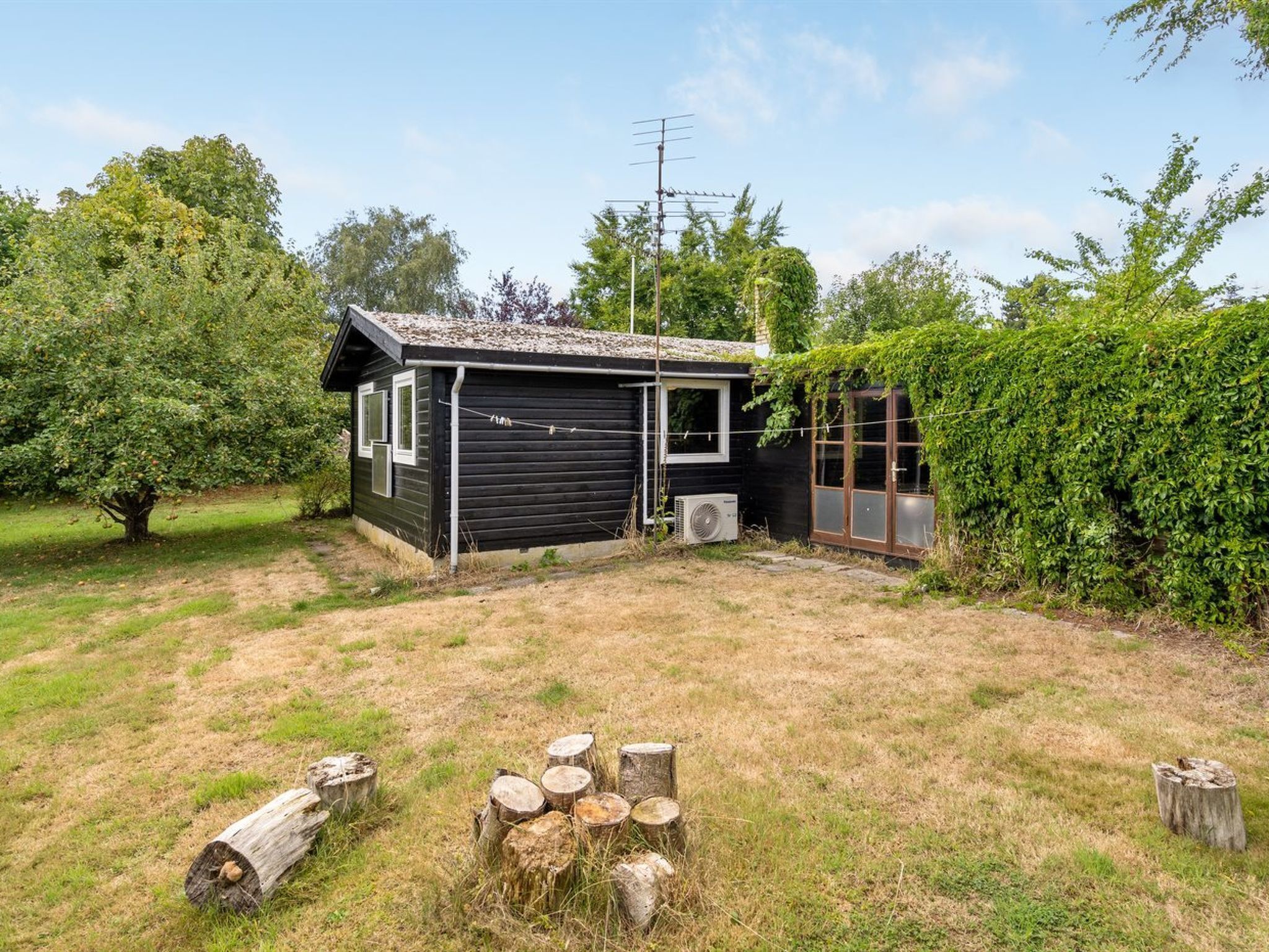Une petite cabane noire avec un toit en pente, une fenêtre et un appareil de climatisation.