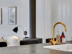 Une cuisine moderne avec un évier blanc, un robinet doré et une bouteille de savon Copenhaag.