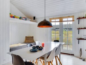 Un coin repas avec une table blanche, des chaises grises et une suspension noire.