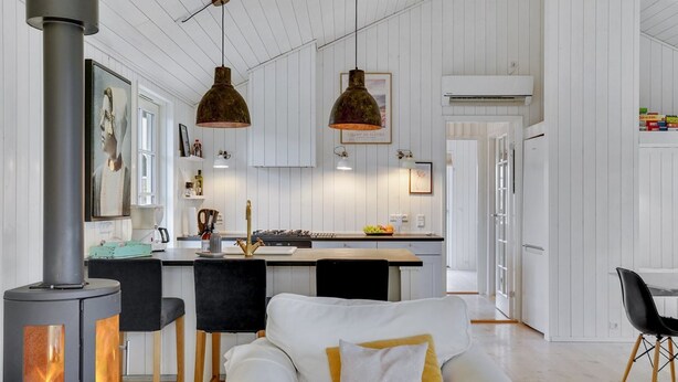 Une cuisine moderne dotée d’un îlot central, de luminaires suspendus et d’un poêle à bois.