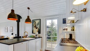 Une cuisine moderne avec des meubles blancs, un plan de travail noir et des luminaires suspendus.