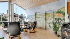 Una sala moderna con chimenea, asientos cómodos y un mural decorativo en la pared.