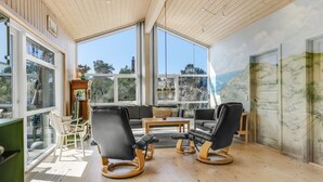 Una habitación amplia con ventanas grandes, techo de madera y vistas al exterior.