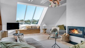 Quarto estilo loft moderno, com um amplo claraboia, área de estar aconchegante, lareira e televisão.