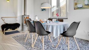 Un comedor moderno con una mesa redonda, sillas negras, un tapete estampado, una manta de piel, una estación de café y un ventanal con vistas.