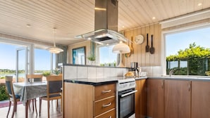 Una cocina moderna con armarios de madera, horno integrado y comedor con mesa y sillas.