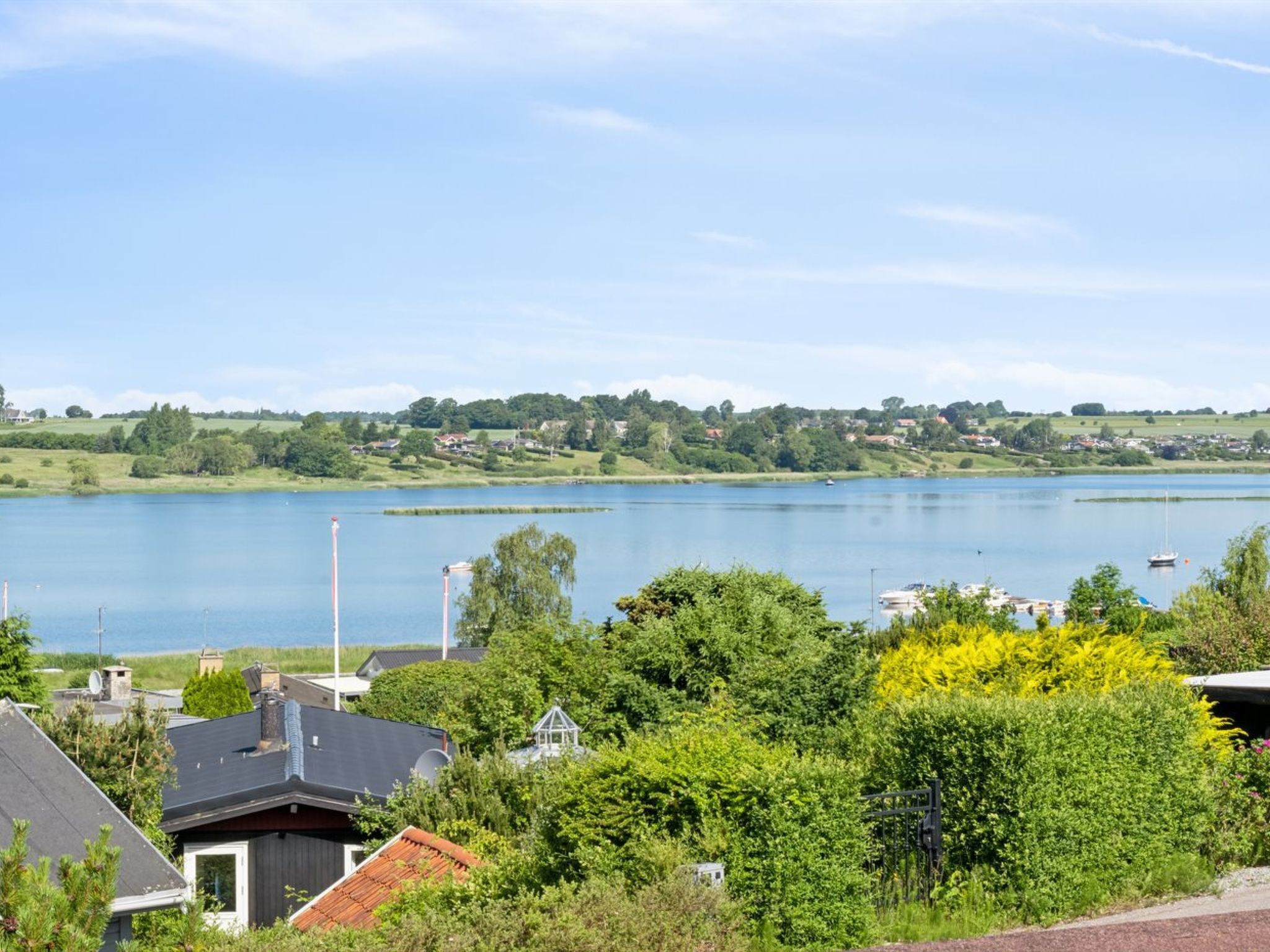 A lakeside view with houses, trees, and boats.