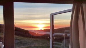 A sunset view from a room with a glass door, a wooden deck, and a grassy landscape. - "Doritea" - 50m from the sea by Interhome (Løkken)