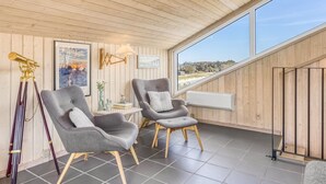 A room with two grey upholstered chairs, a telescope, framed artwork, and a large window offering a view. - "Doritea" - 50m from the sea by Interhome (Løkken)