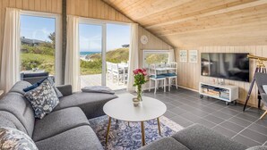 A spacious living area with a large sofa, a round coffee table, a dining table with chairs, a flat-screen TV, and a bookshelf. - "Doritea" - 50m from the sea by Interhome (Løkken)