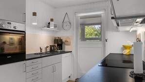 Een moderne keuken met witte kastjes, een zwart aanrecht, een Siemens oven, een koffiezetapparaat en een gele weegschaal.