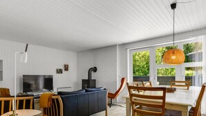 Een moderne woonkamer met een bank, televisie en een eethoek met stoelen en een tafel.