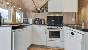Una cocina moderna con armarios blancos, estufa, microondas y cafetera.
