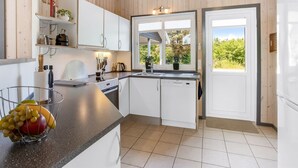 Een moderne keuken met witte kasten, een zwart aanrecht en een raam met uitzicht op groen.