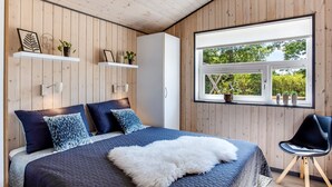 Een slaapkamer met een bed, een stoel, een raam en houten wanden.