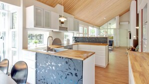 A modern kitchen with wooden cabinets, a central island, and a dining area with chairs. - "Verner" - 500m from the sea by Interhome (Hasle)