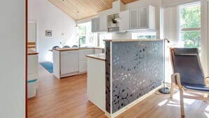 A modern kitchen with white cabinets, a wooden ceiling, and a view of the outdoors. - "Verner" - 500m from the sea by Interhome (Hasle)