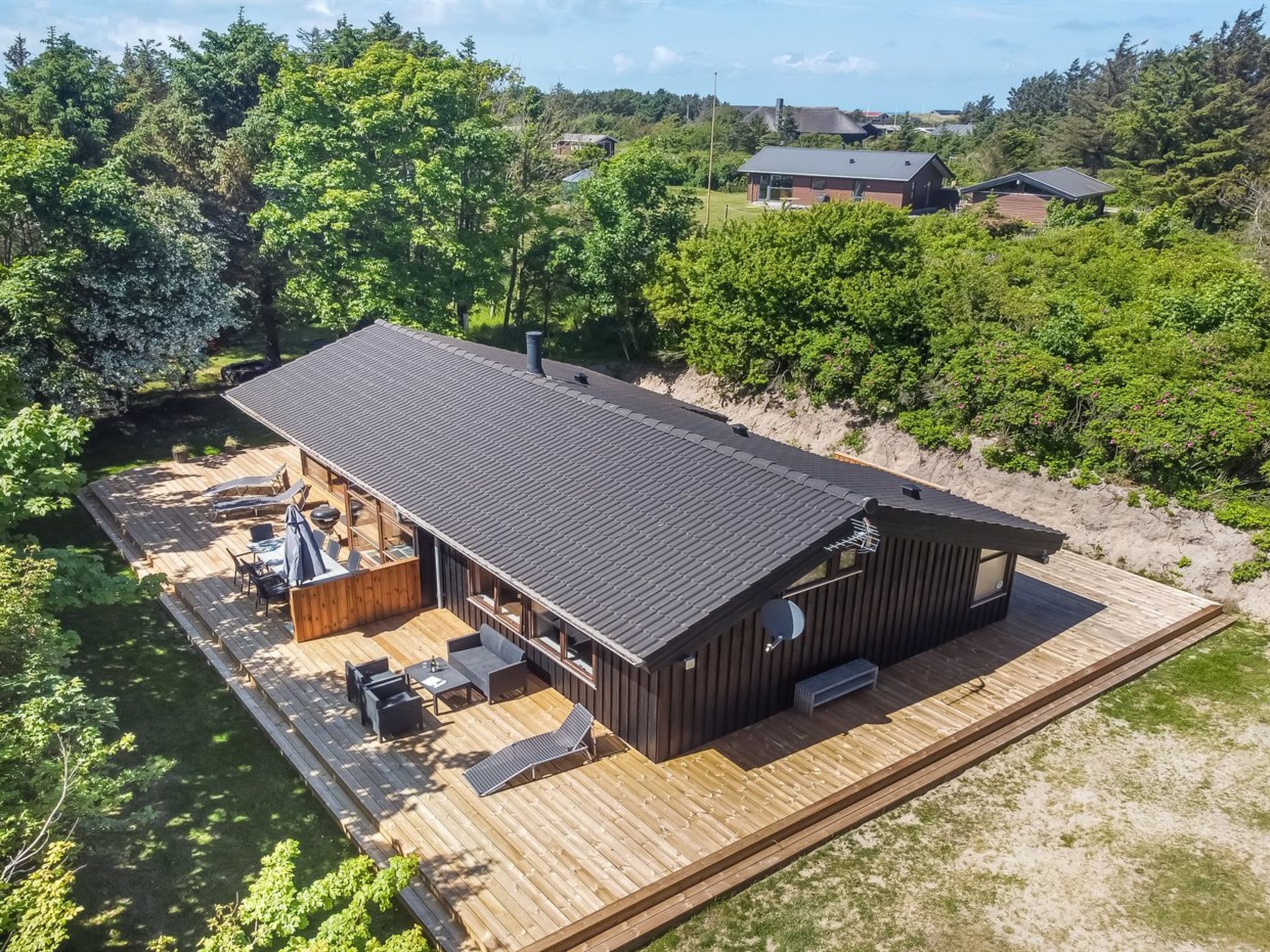 Une cabane dotée d’une terrasse, de meubles d’extérieur et d’une grande fenêtre.