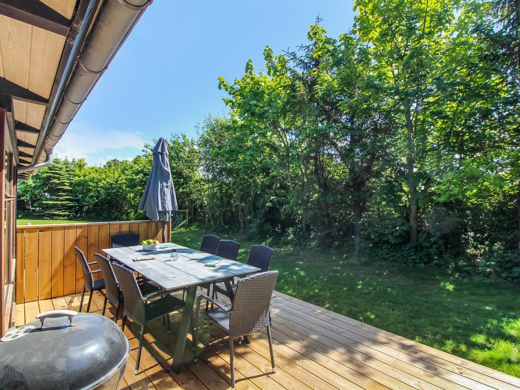 Eine Terrassenanlage im Freien mit Tisch und Stühlen, umgeben von üppiger Bepflanzung.