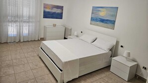 Une chambre à coucher avec un lit, une table de chevet, une commode et deux tableaux accrochés au mur.