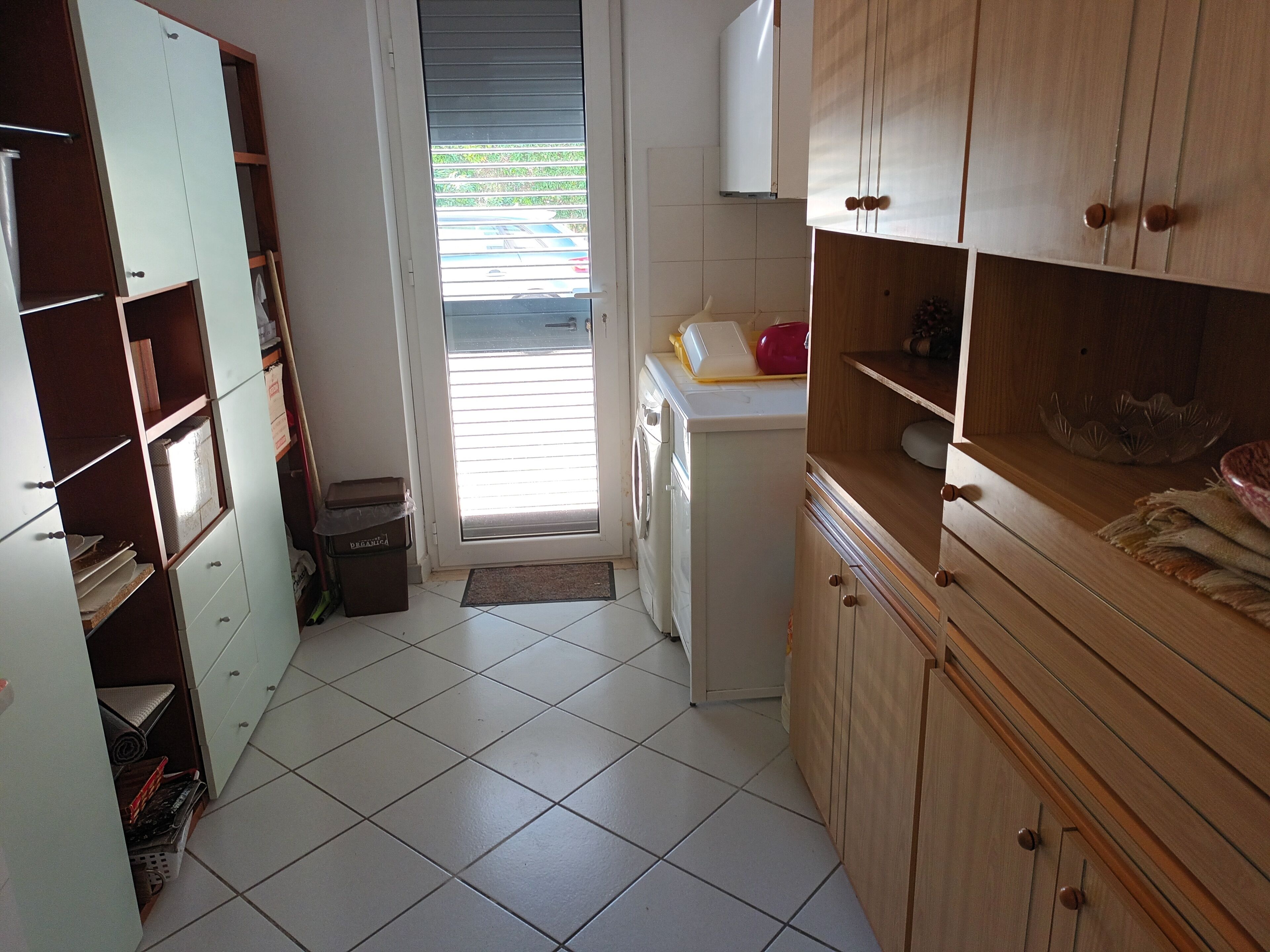 A compact kitchen with white cabinets, a small washing machine, and a door leading to a balcony.