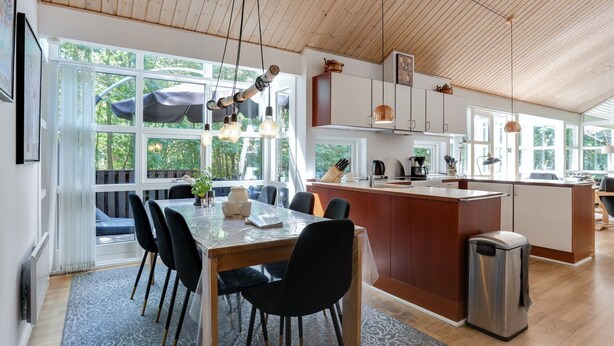Una cocina moderna con armarios de madera, una isla central y un comedor con mesa y sillas.