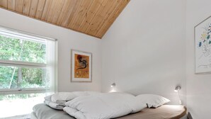 Un dormitorio con cama, ventana y techo de vigas de madera.