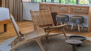 A room with a large window, a wooden desk, two wicker chairs, and a small round table with a decorative bowl. - Villa Elma - 2BR pool villa in Umalas (Kerobokan)