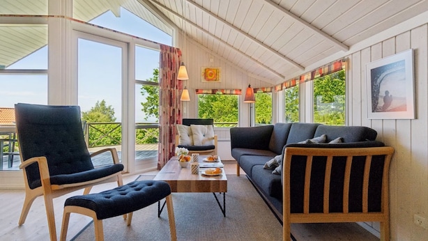 A cozy room with a sofa, two chairs, a table with fruit, and large windows offering a view of greenery. - "Dagmar" - 300m from the sea by Interhome (Hasle)