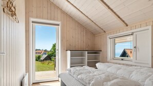A bedroom with a bed, a wardrobe, and a window with a view of houses and greenery. - "Dagmar" - 300m from the sea by Interhome (Hasle)