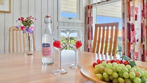 A dining table with a bottle of LORINA, two wine glasses with strawberries, and a plate of grapes. - "Dagmar" - 300m from the sea by Interhome (Hasle)