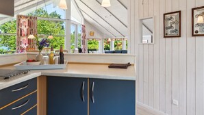 A kitchen with a large island, pendant lights, and a view of greenery outside. - "Dagmar" - 300m from the sea by Interhome (Hasle)