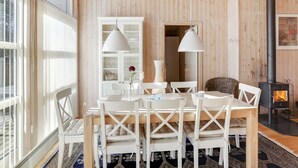 Una habitación acogedora con detalles de madera, una mesa de comedor con sillas, un armario blanco y una chimenea.