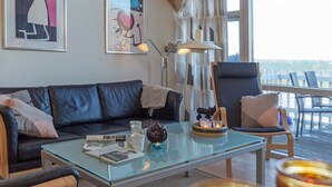 A modern living room with a glass coffee table, leather sofa, and a view of the outdoors. - "Halldora" - 10m from the sea by Interhome (Hasle)