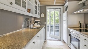 A kitchen with granite countertops, white cabinetry, and a wooden ceiling.
