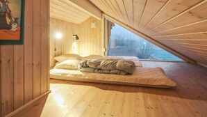 Une chambre mansardée chaleureuse avec des murs en bois et un plafond en pente.