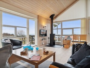 A spacious room with a large window, a fireplace, and a television. - "Paaske" - 350m from the sea by Interhome (Hasle)
