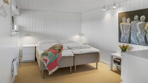 Um quarto moderno com uma cama, mesas de cabeceira, um quadro e uma pequena planta.