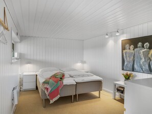 Une chambre à coucher moderne avec un lit, des tables de chevet, un tableau et une petite plante.