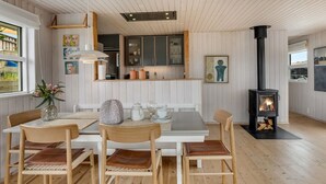 Um interior aconchegante com sala de jantar, cozinha e lareira a lenha.