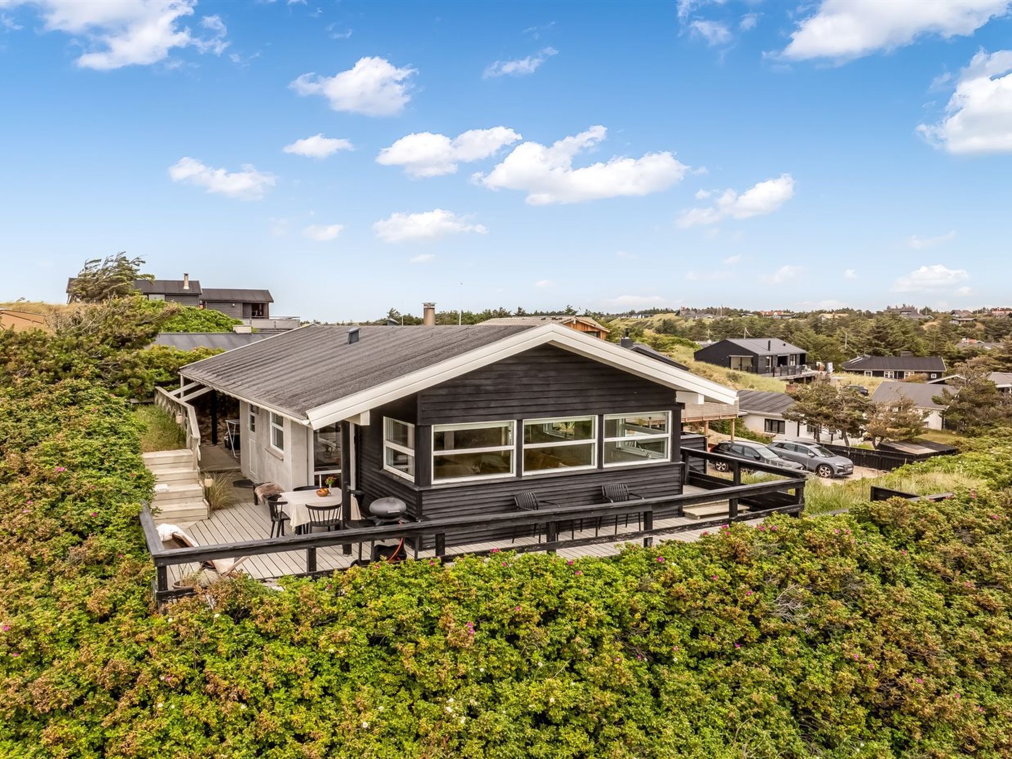 Una casa moderna con terraza, rodeada de vegetación.